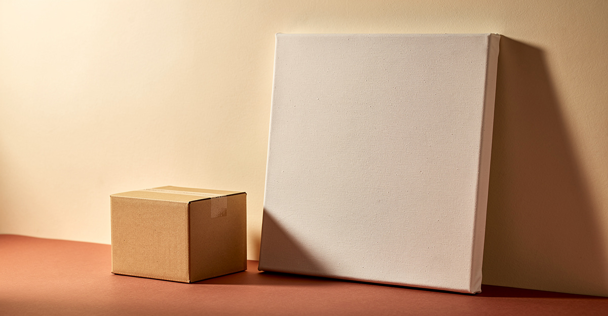 A blank canvas leaning against a warm cream wall beside a small kraft box, representing building a storefront from nothing
